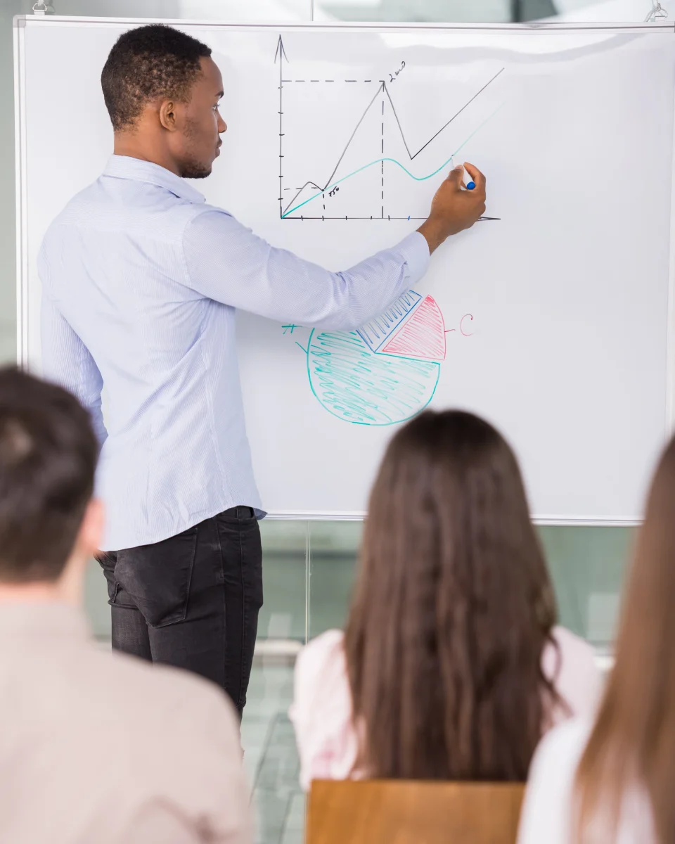 A consultant sketching a plan on a whiteboard during a workshop